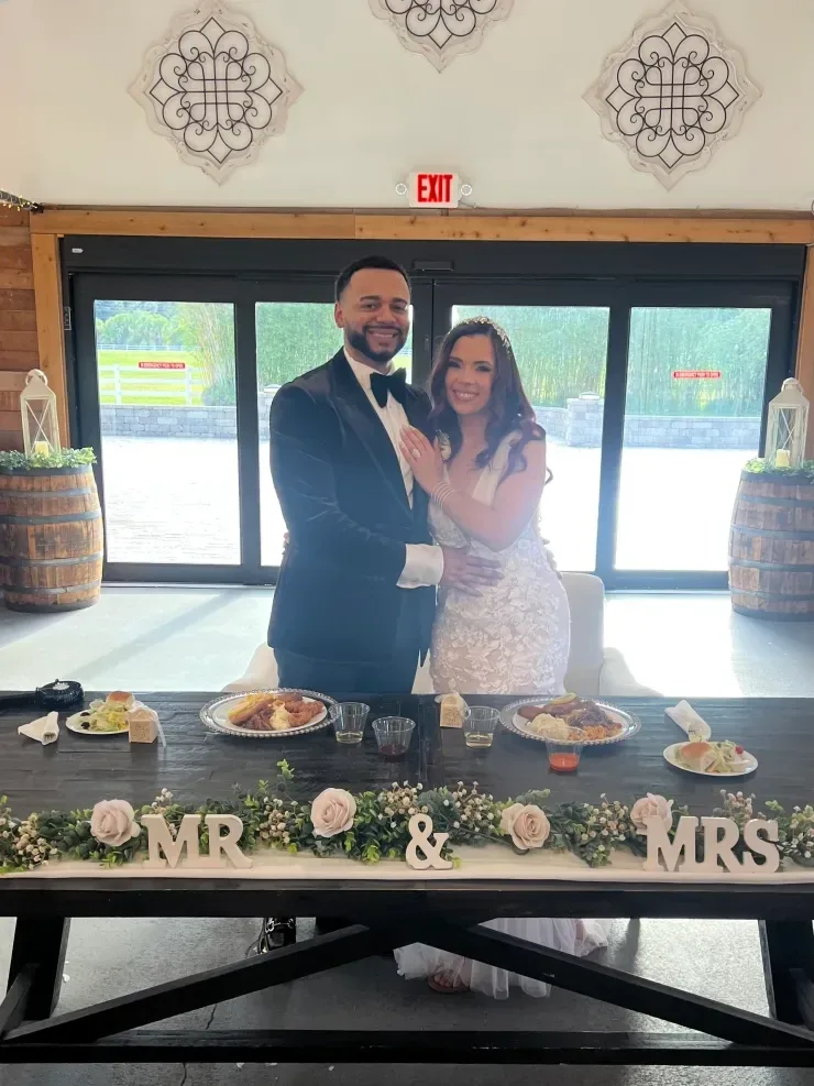 Newlyweds posing at decorated reception table