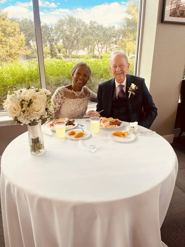 Couple at wedding reception table with white roses and garden view