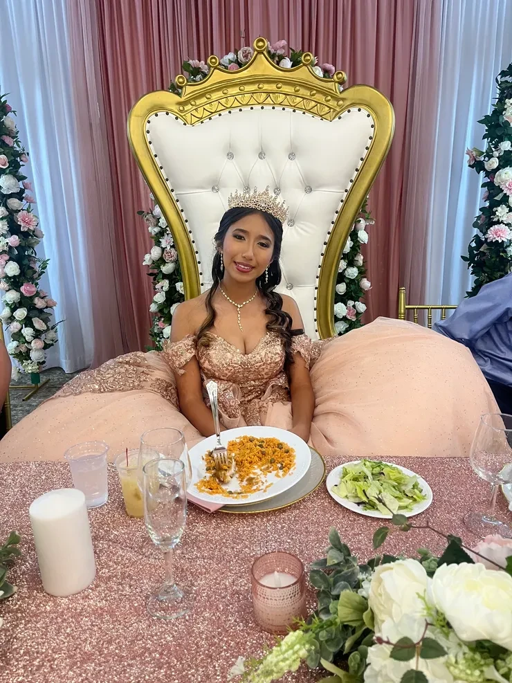 Quinceanera honoree in rose gold gown at throne chair table