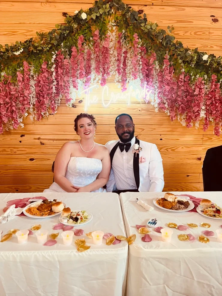 Bride and groom at rustic barn wedding with pink wisteria neon sign backdrop