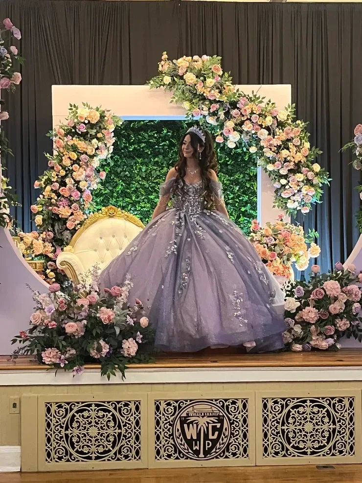 Woman in lavender gown with floral stage backdrop