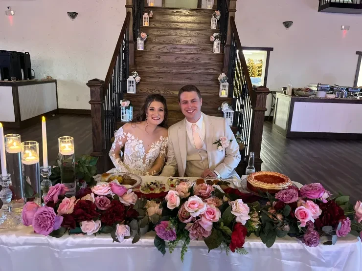 Couple at sweetheart table with colorful floral arrangement and blue ambient lighting