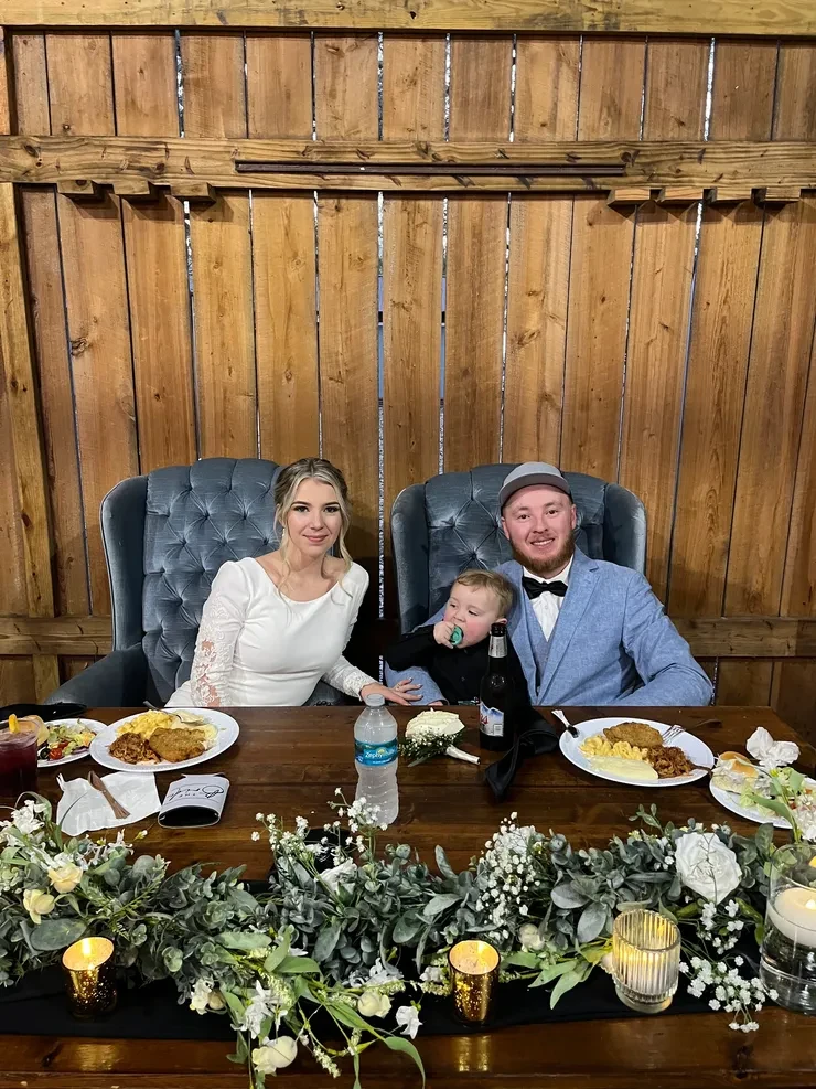 Family at rustic barn wedding sweetheart table with eucalyptus garland