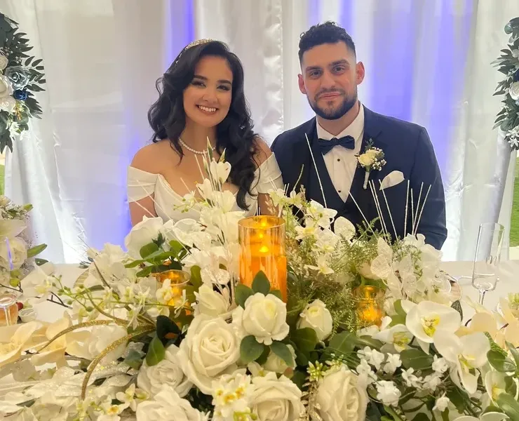 Bride and groom at wedding reception with floral arrangement